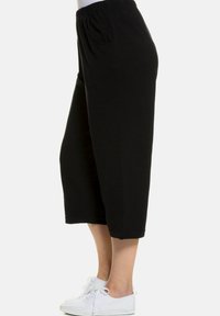 Schwarze Culotte-Hosen mit elastischem Taillenbund, die eine lockere Passform und cropped Länge aufweisen. Das Material scheint weich zu sein und hat minimale sichtbare Nähte.