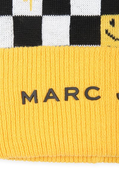 Bonnet en tricot avec une bande côtelée jaune, un motif à carreaux noir et blanc, et un graphique de visage souriant. "MARC J." embossé en lettres noires.