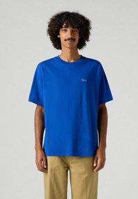 Camiseta de algodón azul de manga corta con cuello redondo y un pequeño bordado blanco de "París" en el pecho. Corte relajado.