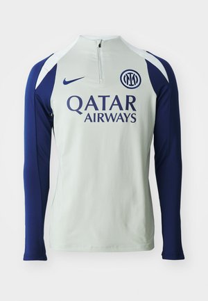 Camisola atlética de mangas compridas em cinza claro com mangas azuis marinho, apresenta um colarinho de meia zíper, logo da Nike e "Qatar Airways" impresso na frente.