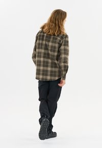 Geruite shirt in olijfgroen en beige, gemaakt van een zachte stof. Lange mouwen, met knopen afgebonden manchet en een losse pasvorm. G　dragen met zwarte broek en schoeisel.