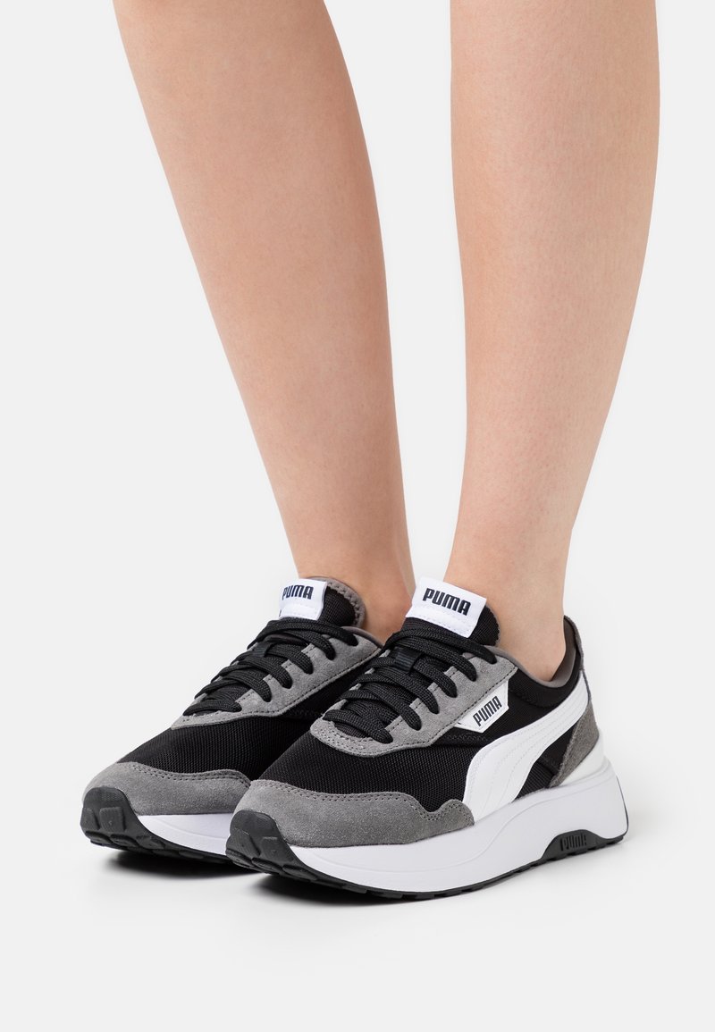 Černé a šedé tenisky s texturovaným svrškem z semiše a síťoviny, bílé detaily a tlustá bílá podrážka. Logo PUMA na jazyku.