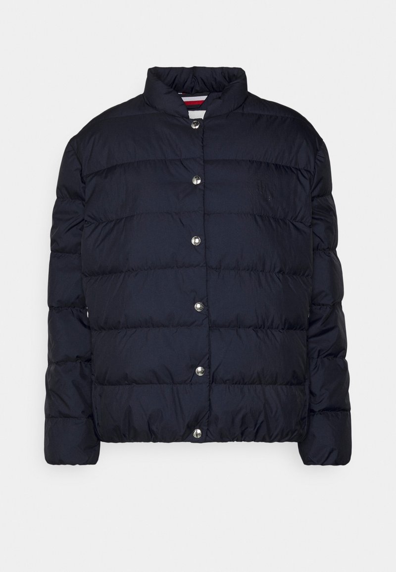 Navy puffer-jakke med høj krave, trykknaplukning, kviltet tekstur og diskret logo-detail på brystet.