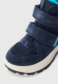 Niebieskie dziecięce trampki z rzepami, siateczkową cholewką, zamszowymi detalami i grubą białą podeszwą z czarnym bieżnikiem na białym tle.