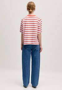 Gestreiftes T-Shirt in Rot und Weiß, cropped Design, kurze Ärmel. Kombiniert mit hoch taillierten, weiten blauen Jeans.