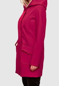 Pink hooded jacket with a front zipper, side pockets, and textured fabric. Features stitching accents and branding on the chest.