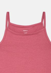 Ροζ αμάνικο μπλουζάκι με λεπτές τιράντες, φτιαγμένο από μαλακό ύφασμα, με στρογγυλή λαιμόκοψη και λεπτή υφή. Ετικέτ�α ορατή μέσα από τον γιακά.