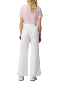 Białe, szerokie dżinsy z wysokim stanem, z tylnymi kieszeniami oraz metką. W połączeniu z jasnoróżową koszulką w paski.