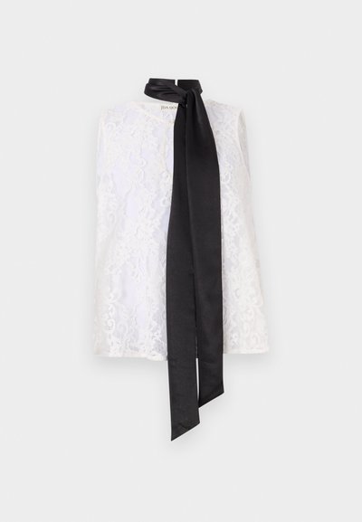 White lace top featuring a high neckline and a black satin ribbon tied at the collar. Intricate lace pattern and smooth texture.