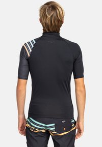 Kortärmad svart rash guard med hög krage. Har färgglada randade detaljer på vänster axel och sidan, tillverkad av stretchigt material.