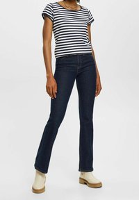 Maglietta a righe navy e bianca a maniche corte abbinata a jeans palazzo blu scuro e stivaletti beige, caratterizzata da una vestibilità comoda e maniche arrotolate.