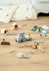 Puitunud mängufarm komplekt, mis sisaldab sinist traktorit ratastega, erinevaid loomafiguure, taluhooneid ja lisandeid pastellvärvides puidust põrandal.