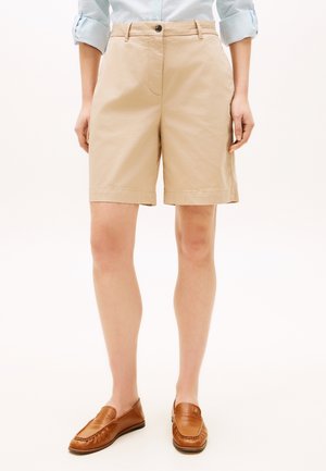 Beige Baumwollshorts mit geradem Schnitt, Vordertaschen und einem Knopfverschluss, kombiniert mit braunen Lederloafern.
