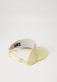Boné amarelo com aba curva, faixa ajustável e forro interior branco. Apresenta uma etiqueta com o logótipo da Adidas no interior.