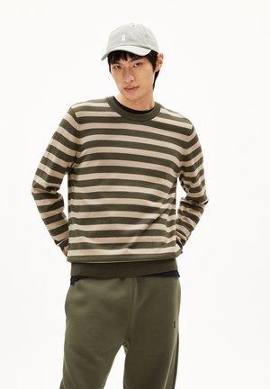 Gestreifter Pullover in Oliv und Beige, Rundhalsausschnitt, gerippte Bündchen und Saum. Kombiniert mit passenden olivfarbenen Jogginghosen und einer hellgrauen Cap mit Logo.