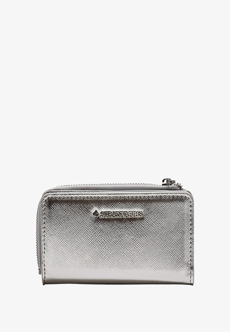 Hopeinen metallinen lompakko, jossa on teksturoitu pinta, vetoketjukiinnitys ja logotunnus. Kompakti suorakaiteen muotoinen, sopii korteille ja kolikoille.