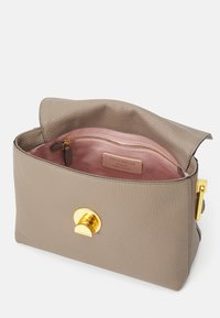 Borsa a mano in pelle beige con finitura texturizzata, dotata di chiusura a bottone dorato e interno foderato in rosa con tasca zip.