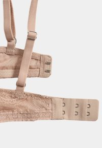 Tirante de sujetador de encaje beige con elementos ajustables, herrajes de metal, tela texturizada y cierre de gancho y ojal para ajuste de tamaño.