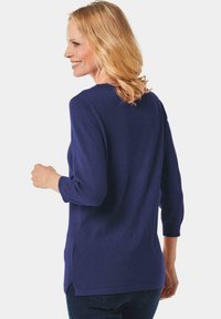 Navyblauer, weicher Strickpullover mit Dreiviertelärmeln, rundem Halsausschnitt und seitlichen Schlitzen am Saum für zusätzlichen Komfort.