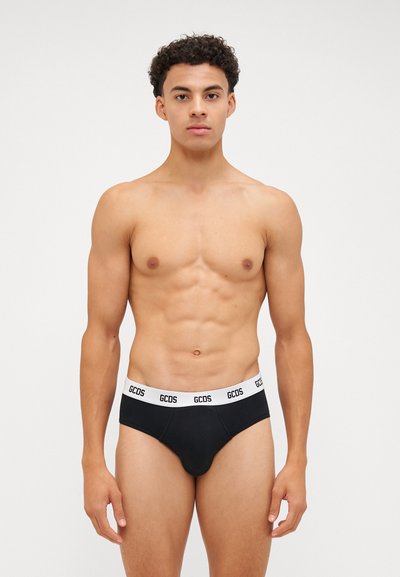 Slip in cotone nero con una fascia in vita bianca con logo, caratterizzati da una vestibilità aderente e una texture liscia. Il design mette in evidenza una forma classica del slip.