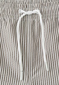 Material maro și alb cu dungi verticale pentru pantaloni scurți, cu șnur alb legat prin ochiuri metalice la talia elastică.