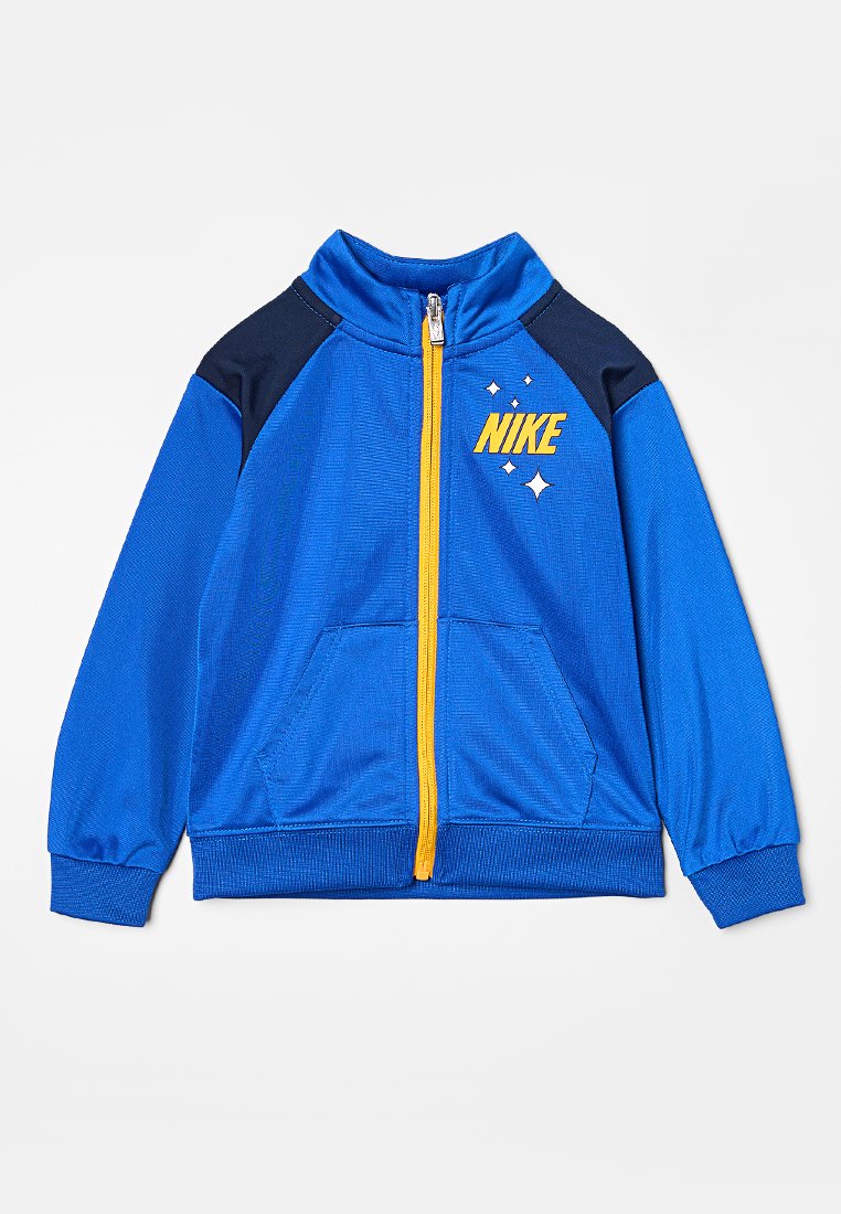 Giacca blu con zip, dettagli navy, polsini a coste e una zip gialla. Presenta un logo Nike e dettagli a stella sulla parte anteriore.