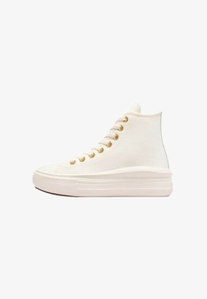 Zapatillas altas de lona blanca con suela gruesa blanca, ojales dorados y textura suave; cuentan con una puntera redondeada y un diseño minimalista.