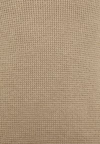 Tissu tricoté beige avec une texture, un tissage ouvert et un motif horizontal régulier, adapté aux vêtements ou aux accessoires.