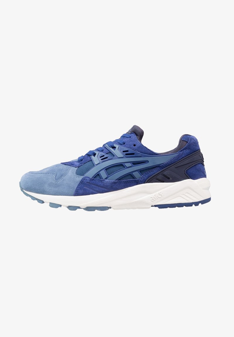 Chaussures de sport bleues en daim et mesh, avec un design en couches, une fermeture à lacets et une semelle intermédiaire blanche dotée d'une semelle extérieure en caoutchouc texturé.