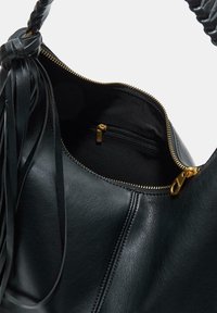 Borsa a mano in pelle nera con manico intrecciato e dettagli frangiati. Dotata di chiusura con zip dorata e tasca interna per una sicura conservazione.