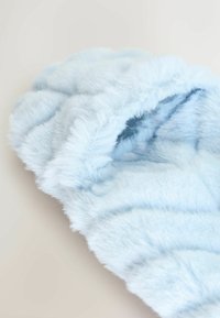 Helles blaugraues Kunstfell mit einer weichen, flauschigen Textur; zeigt wellenförmige, sich wellende Muster, die ein plüschiges, gemütliches Aussehen erzeugen.