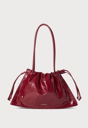 Red patent leather tote bag with a triangular shape, gathered drawstring top, and two long handles. Gold logo detail on the front.