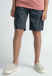 Tummanharmaat cargo-shortsit, joissa on sivutaskut, valmistettu kevyestä kankaasta. Yhdistetty harmaisiin liukuhihnasandaaleihin, sopivat rentoon pukeutumiseen.