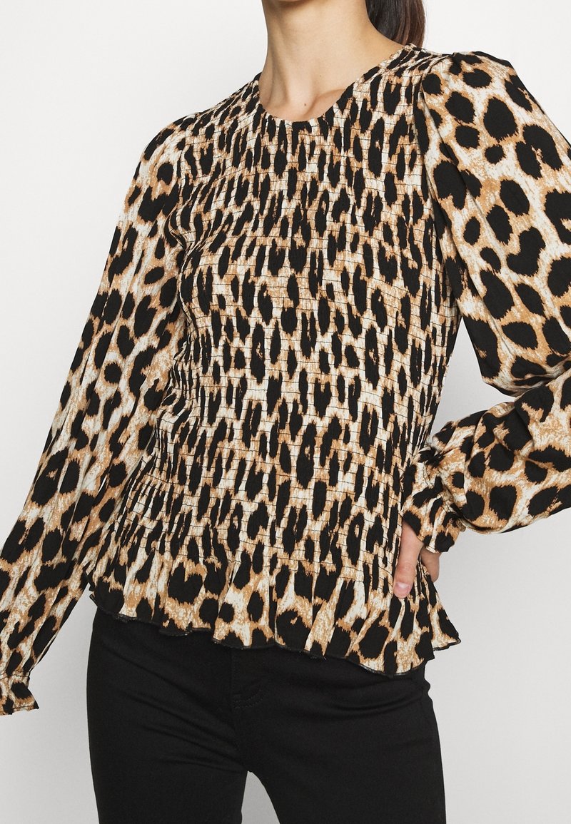 Blusa con stampa leopardata nei toni del nero e del beige, caratterizzata da un tessuto strutturato, dettagli smock, maniche lunghe e orlo arricciato.