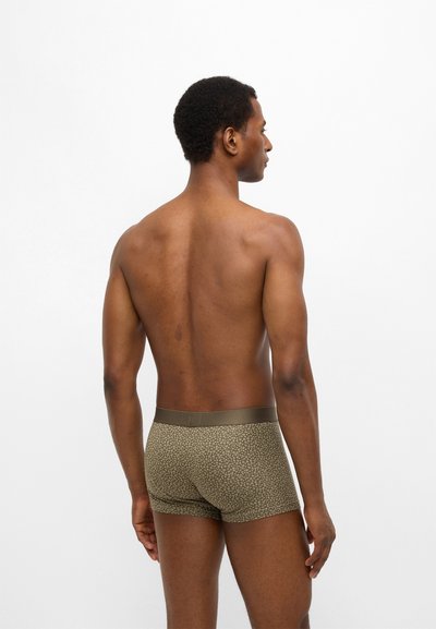 Χακί ανδρικά μποξεράκια με βουλωτό μοτίβο, μαλακό ύφασμα και ελαστική μέση, φωτογραφημένα από πίσω, με ορατό δέρμα μοντέλου.