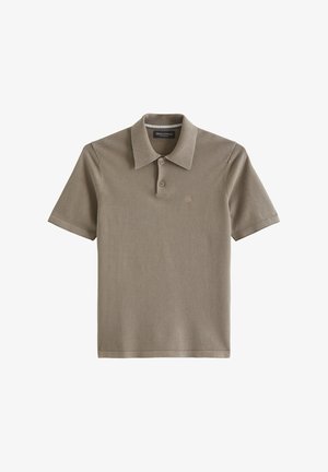 Beżowa koszulka polo z krótkim rękawem, dwoma guzikami, kołnierzykiem typu spread i subtelnym haftowanym logo na lewej piersi.