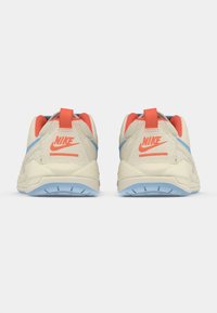 Par bežnih Nike tenisica s koraljnim akcentima i plavim potplatima, prikazanih s leđa na bijeloj pozadini.