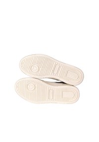 Sneaker bianche con una suola in gomma testurizzata, dotate di un logo a forma di cuore e dettagli di marca. La suola presenta scanalature e righe a contrasto.