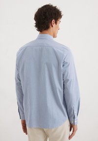 Blau-weiß gestreifte Button-down-Hemd mit einem Kentkragen, langen Ärmeln und abgerundetem Saum. Verfügt über weiße Knöpfe an den Manschetten.