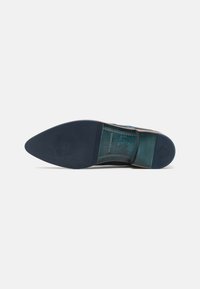 Suola di scarpa in pelle di colore marrone scuro con forma appuntita. Presenta una sezione testurizzata e un dettaglio con logo in rilievo. Finitura liscia su tutta la superficie.