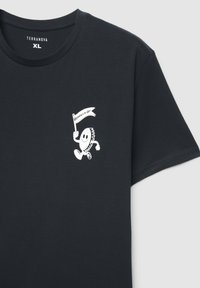 Czarna bawełniana koszulka z małym białym nadrukiem postaci trzymającej flagę z napisem „Living to be Lite” na wysokości klatki piersiowej.