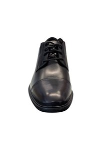 Zapato de vestir de cuero negro con diseño de cordones, puntera redonda, textura suave y sutileza en el detalle de costura a lo largo de la suela.