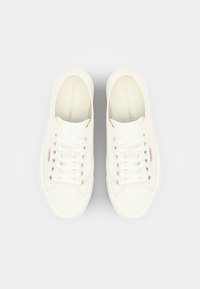 Sneakers bianchi in canvas con punte rotonde, lacci piatti e un sottile dettaglio del logo sulla linguetta; suole in gomma con una finitura testurizzata.