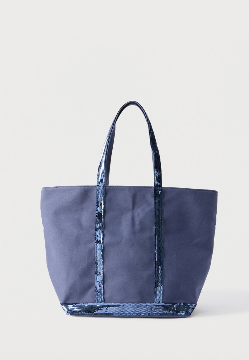 Sac fourre-tout en toile bleu marine avec des poignées et un bord ornés de sequins brillants, debout à la verticale sur un fond blanc.