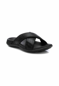 Sandalias de slide negras con tiras cruzadas hechas de material sintético perforado. Suela plana, textura suave y diseño discreto.