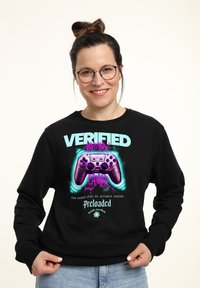 Felpa nera con una grafica vivace di un controller di gioco, testo che recita "GAMER VERIFICATO" e accenti viola e turchese brillanti.