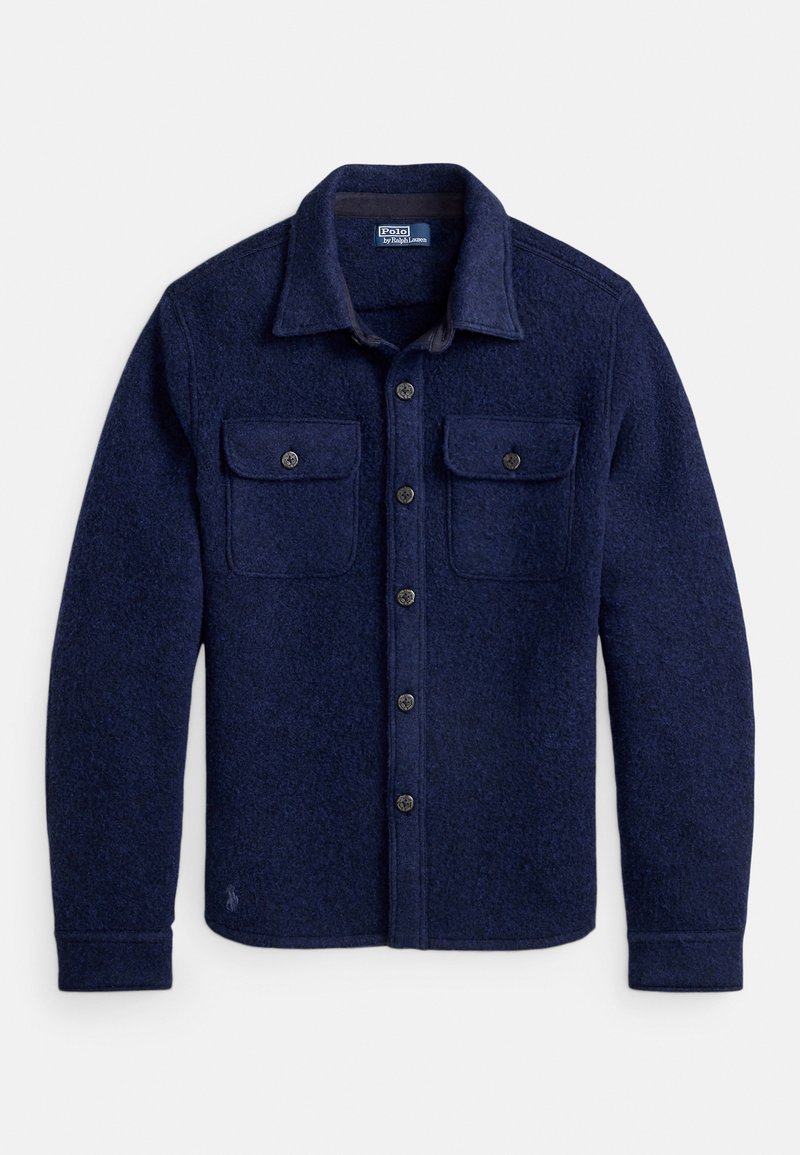 Chemise veste en flanelle bleu marine avec fermeture à boutons sur le devant, deux poches poitrine et tissu texturé. Comprend un col avec revers et des boutons décoratifs.
