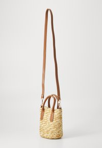 Sac en paille tressée rond avec des anses et des accents en cuir marron. Présente une petite taille, une surface texturée et des poignées robustes pour le transport.