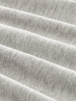 Lähedalt vaadatud pehme, heledashall trikotaažkangas, milles on nähtavad südamekujulised ribid ja diagonaalsed voltimised.