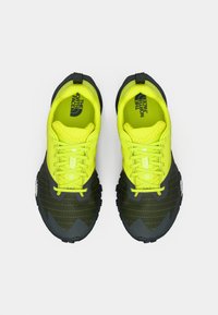 Παπούτσια για τρέξιμο σε μονοπάτια σε πράσινο λάιμ με διαπνέον πλέγμα, μαύρες λεπτομέρειες, υφή στη σόλα και ενισχυμένη μύτη· διαθέτουν λογότυπο στο πλάι και στην εσωτερική σόλα.